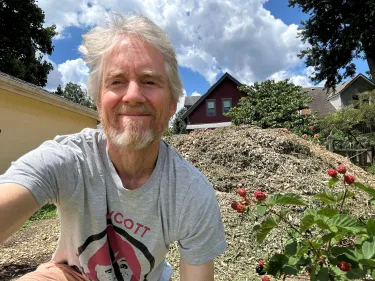 Author, blackberry bush, wood chips pile, and house in background
