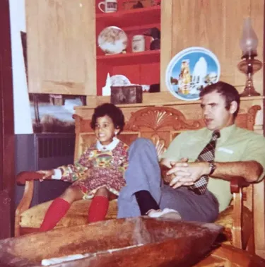 Little girl smiling in vintage photo while seated next to dad