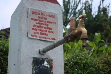 A pipe and faucet extending from a pillar with red lettering on it