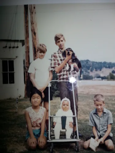 Vintage photo of baby in stroller while surrounded by a little girl and some boys, one holding a dog