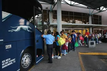 A long line of people wait to board a charter bus