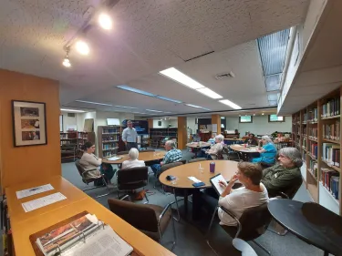 Attendees of Staniunas's presentation sit around four circular tables in the Presbyterian Heritage Center in Western North Carolina.