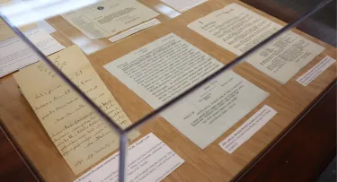 A photo of archival documents laid out underneath a glass case display when the traveling exhibit was hosted at PHS in 2024.