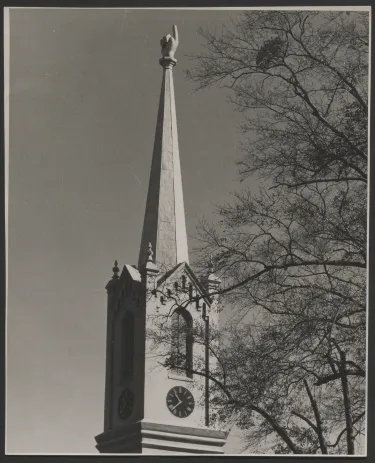 A church building with a 10-foot-tall gold-leaf-covered sculpture of a human hand at the top of its steeple. 