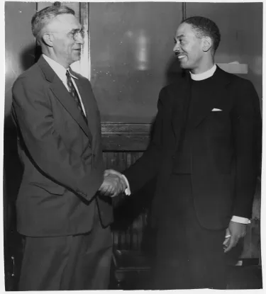 Rev. Robert Pierre Johnson (right) shakes hands with a white besuited gentleman at his installation ceremony as pastor of 15th Street Presbyterian Church in Washington, D.C.