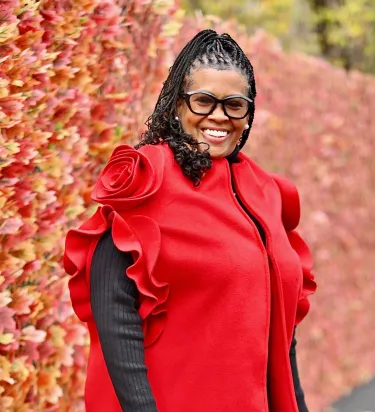 Woman in braids and red ruffled blouse smiles