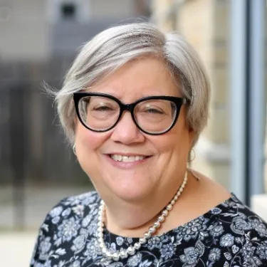 Head shot of woman in glasses and patterned shirt smiling