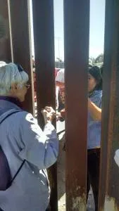 Mary and Cindy sharing bread through the wall at the Agape Feast