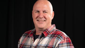 A man in a plaid shirt against a black background