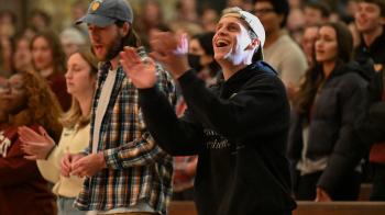 A young adult claps hands during worship