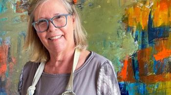 A woman stands in front of an abstract painting