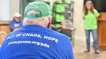 a man in a blue shirt sits with his back to the camera