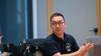 A man in glasses wearing a black shirt claps at a table