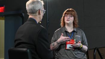 person with back to camera on left and person on right facing camera and gesturing