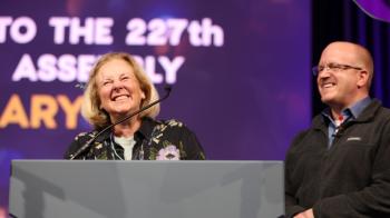 Constitutional Interpretation Committee leaders Miriam Hollar (left) &amp; Joseph Genau (right) report the assembly's consideration of the committee's business is complete during plenary 6 on June 29. Photo by Jim Deweese