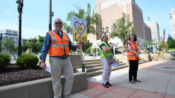 three people with bright vests smiling at camera
