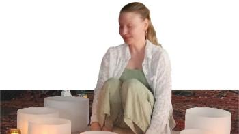A woman sits meditatively among candles.