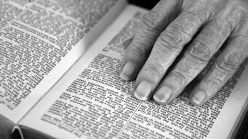 Senior Woman's hand on her open Bible.