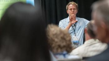 A man speaks to a room full of people