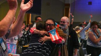 Following the announcement that GA228 will be held in Puerto Rico, two commissioners share a celebratory hug. Photos by Kristen Gaydos. 