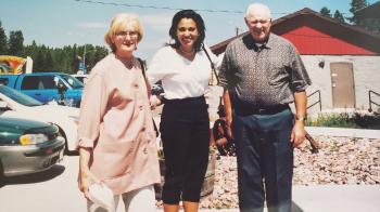 Adult woman in white shirt standing in between her parents