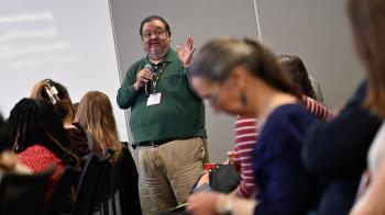 A man in a green shirt speaks into a microphone
