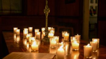 A table full of candles and a cross.