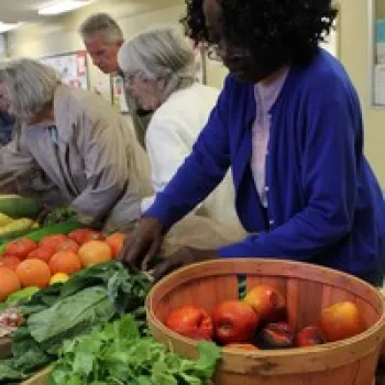 woman picking fresh vegetables out of baskets