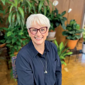 A photo of Rev. Charlotte Lohrenz with plants in the background. 