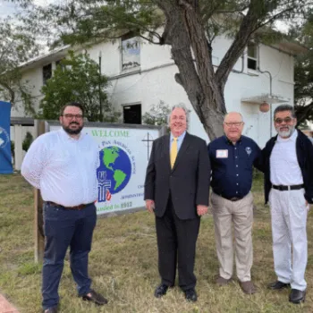 Four men standing in front of the Pan American School sign