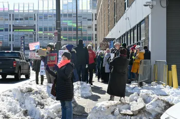 Vigil attendees and protesters appeal to traffic on a busy street.
