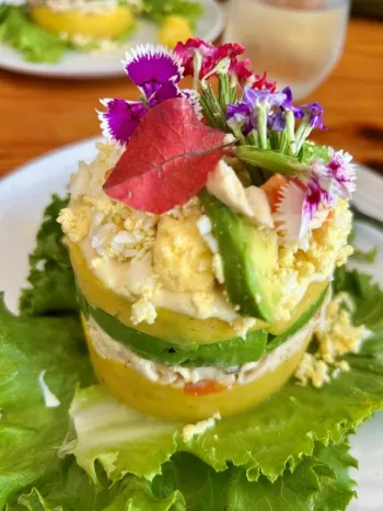 Peruvian potato dish with chicken salad, eggs and edible flowers