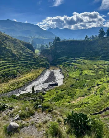 Valley with river flowing through with terraces along the sides of hills and mountains in the distance