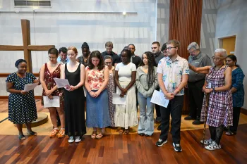 A group of young people bow their heads in prayer