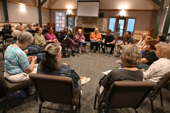 A group of people sit in a circle in a room, engaged in a discussion.