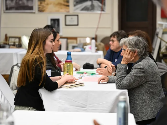Group of women chat across table from each other