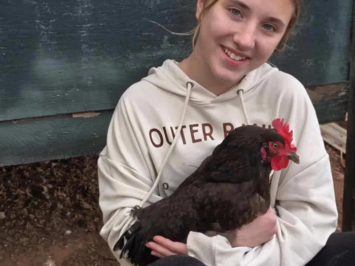 smiling young girl holding red hen
