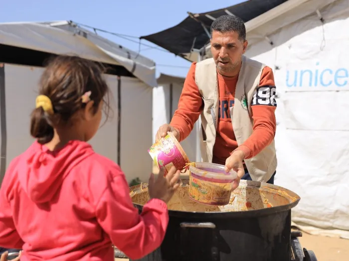 Man serves food to young girl in Gaza