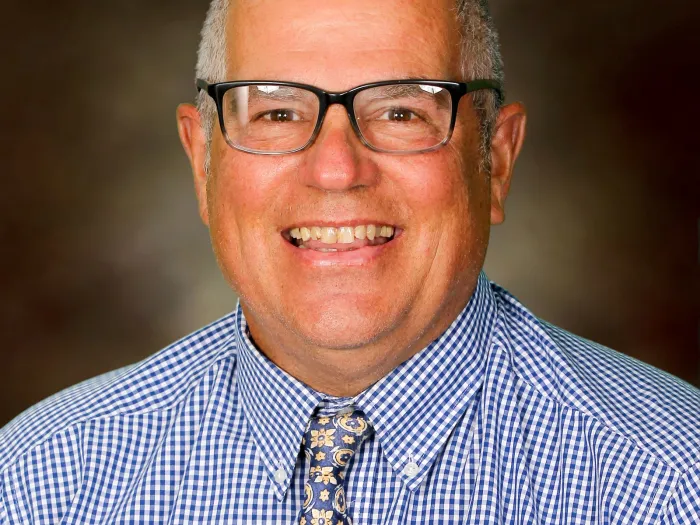 Headshot of middle-aged white man in blue shirt with tie