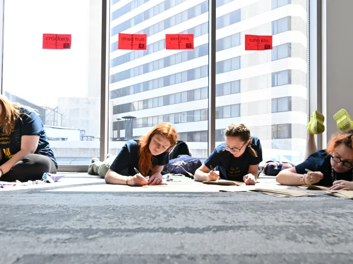 Young people sprawled out on the carpet writing things on sacks