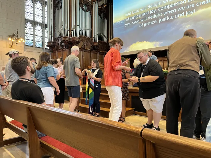 People gather for communion in a church. LGBTQIA+ affirming stole on clergy