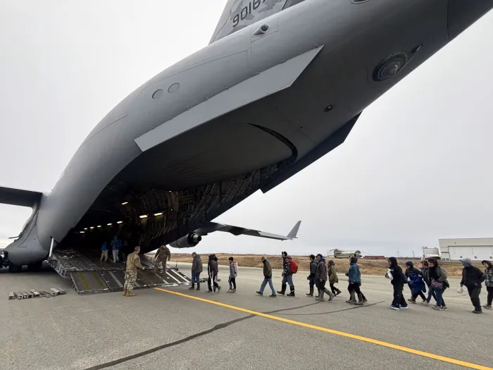 A line of evacuees walking up to a plane