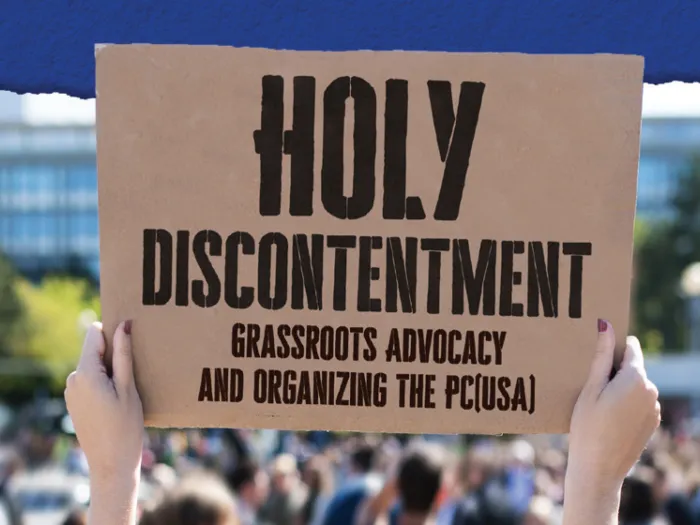 A cardboard sign being held up in the air at a protest