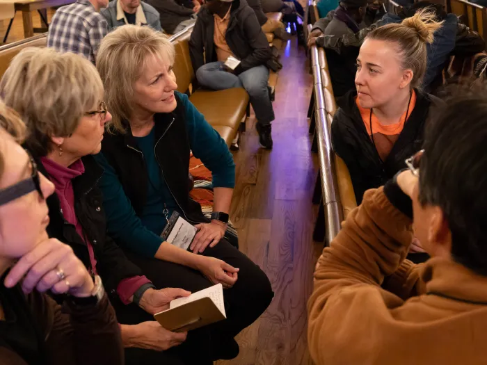Rev. Karen Rohrer wears orange in worship talking with others.
