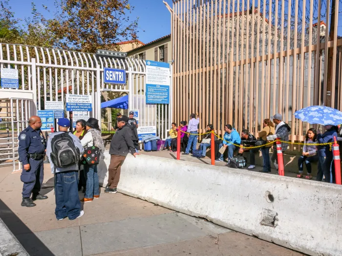 A group of people wait in Tijuana, Mexico at a border crossing to the United States.