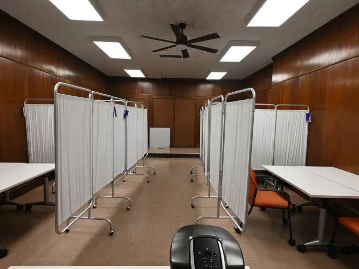 White screens and tables set up in a room with wood paneling