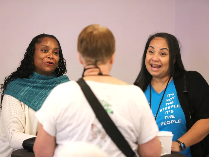 Two smiling women looking at third person at a reception