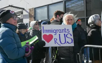 Vigil participant stands with sign outside of Philadelphia Immigration and Customs Enforcement Offices. 
