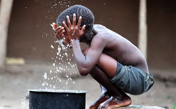 boy splashing water on his face and head