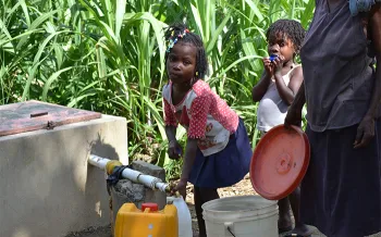 children retrieving water from a well spigot